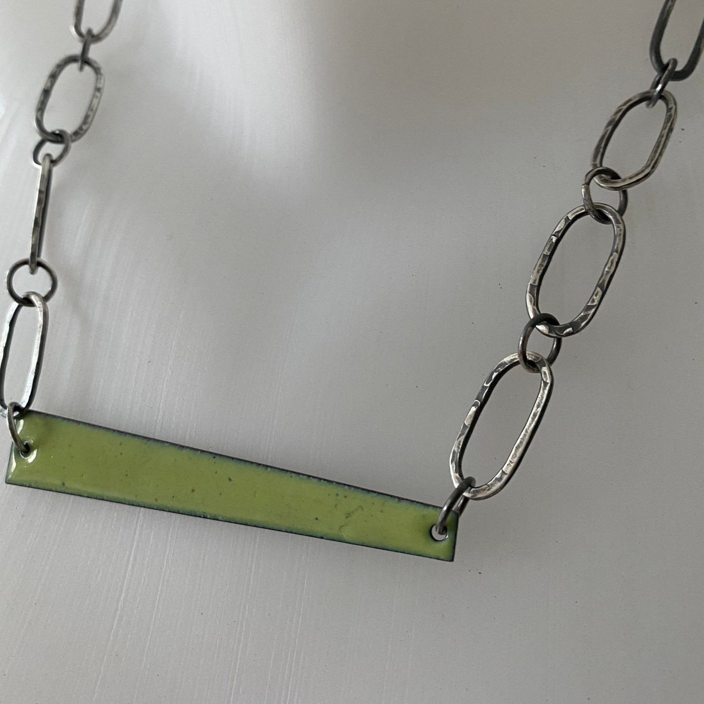 Close up of lime green enamel and oxidised  necklace