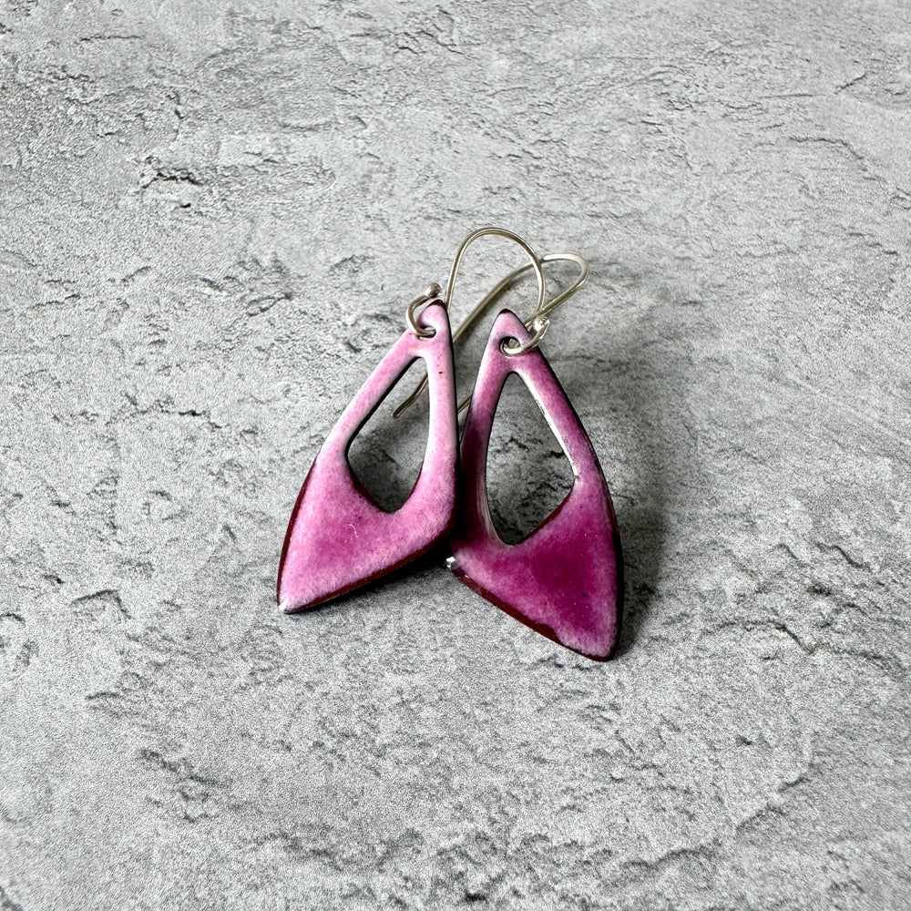 Pink earrings on a gray textured surface