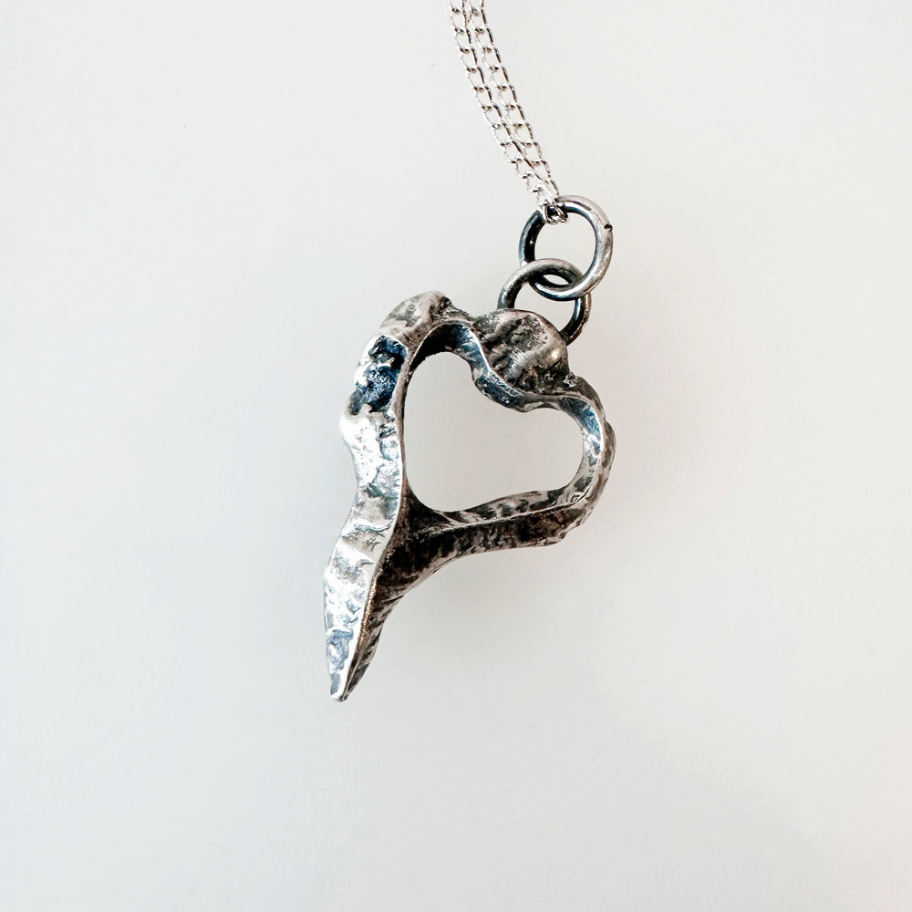 Silver heart-shaped pendant on a chain against a white background