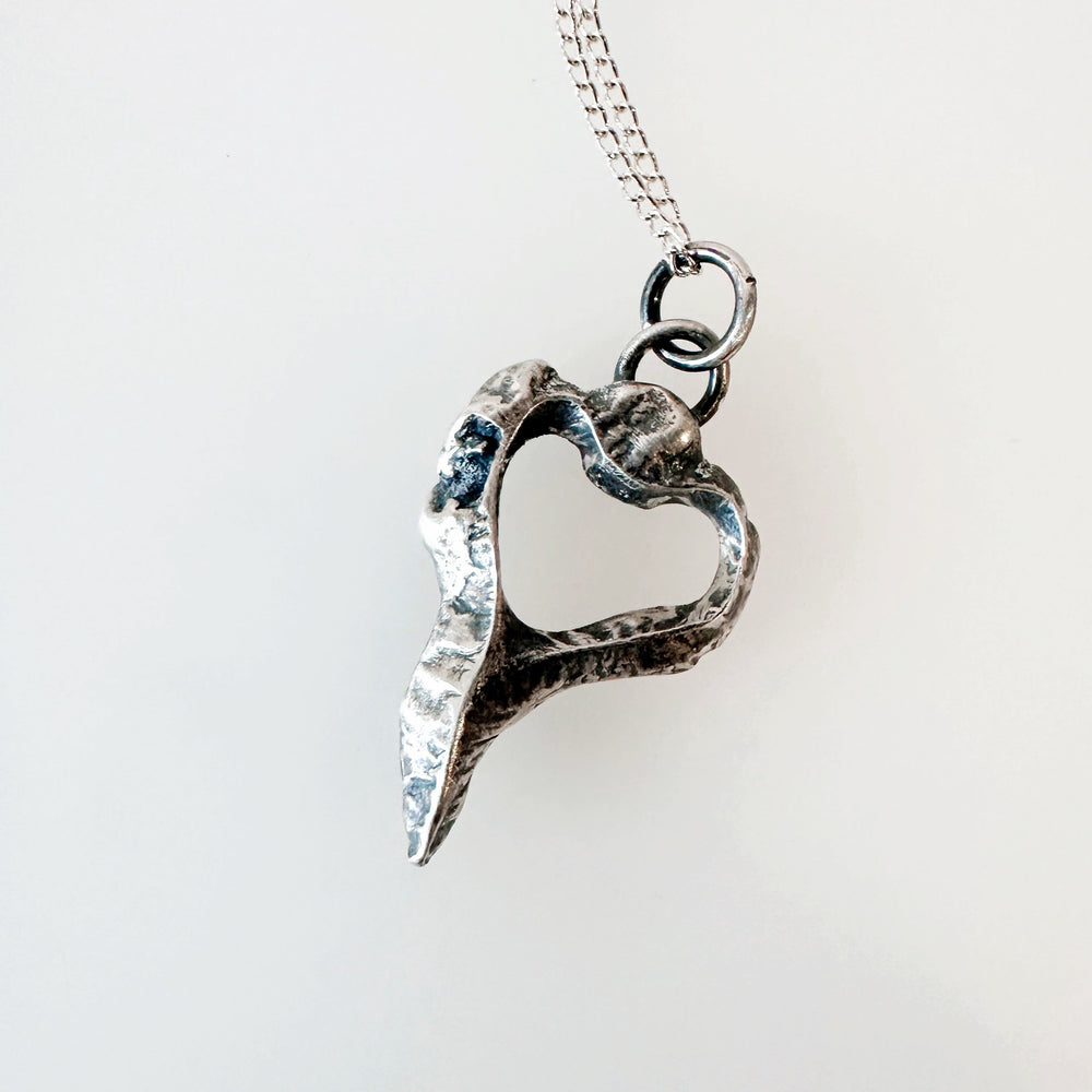 Silver heart-shaped pendant on a chain against a white background