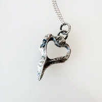 Silver heart-shaped pendant on a chain against a white background