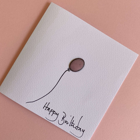 small pink balloon on the front of white greeting card with Happy Birthday  hand written text